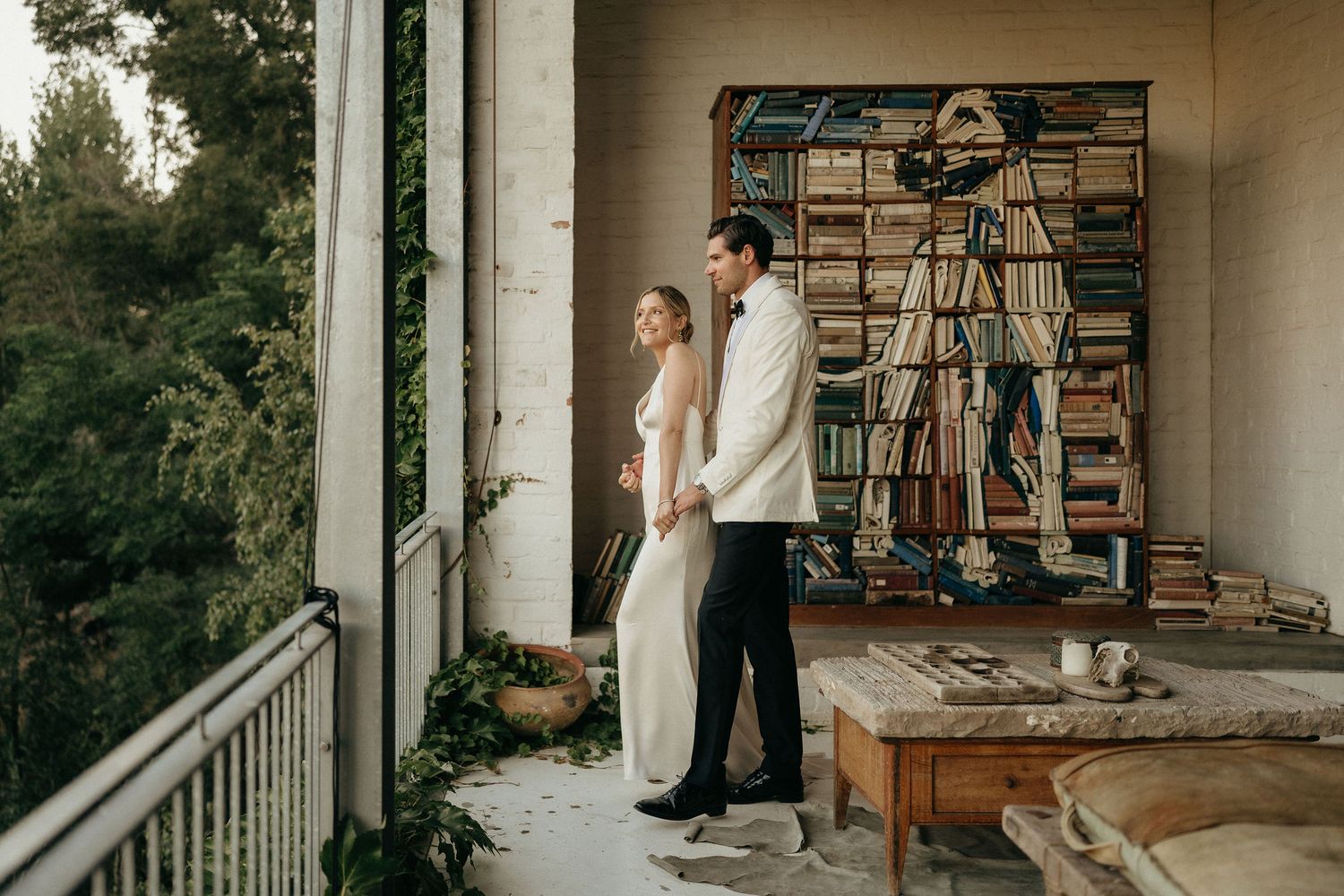 Couple embracing in a cozy home interior with bookshelves and natural lighting.