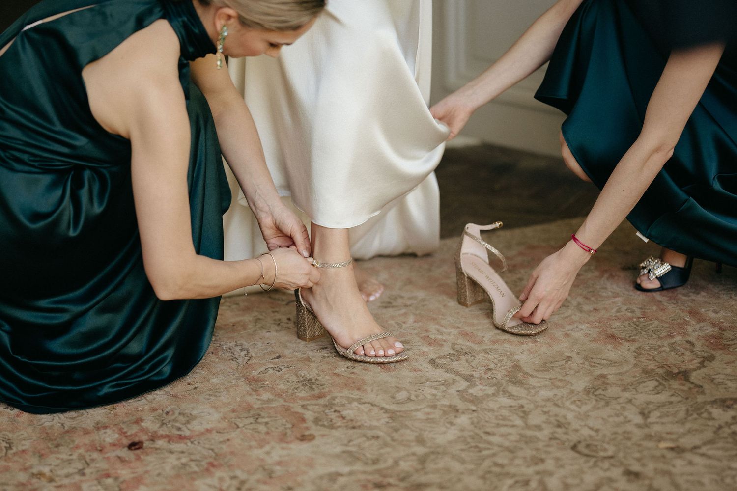 Bridesmaids in navy dresses and bride in white gown show off their sandals and heels in a group photo.