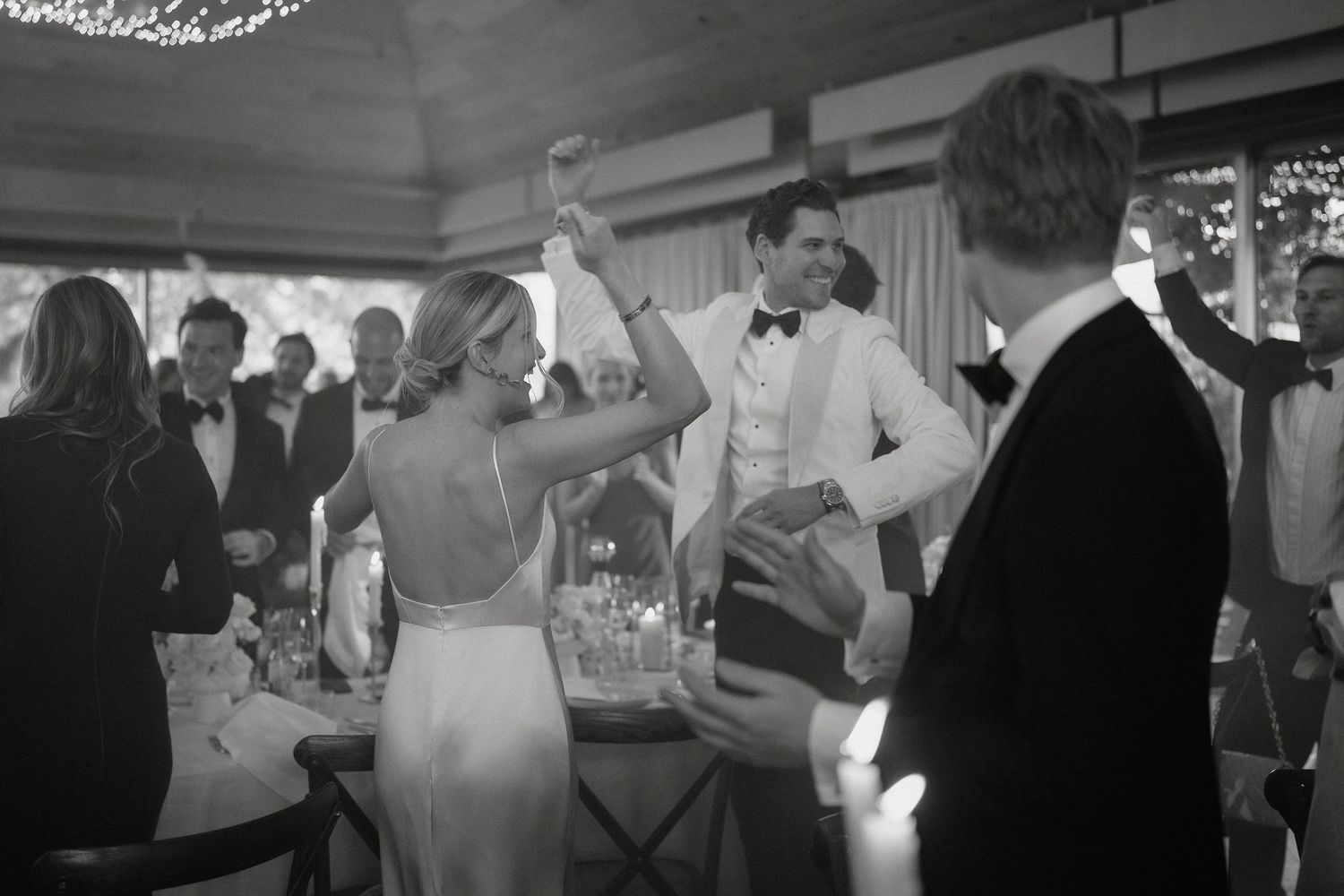 Black and white wedding reception photos show guests dancing and celebrating at an elegant venue.
