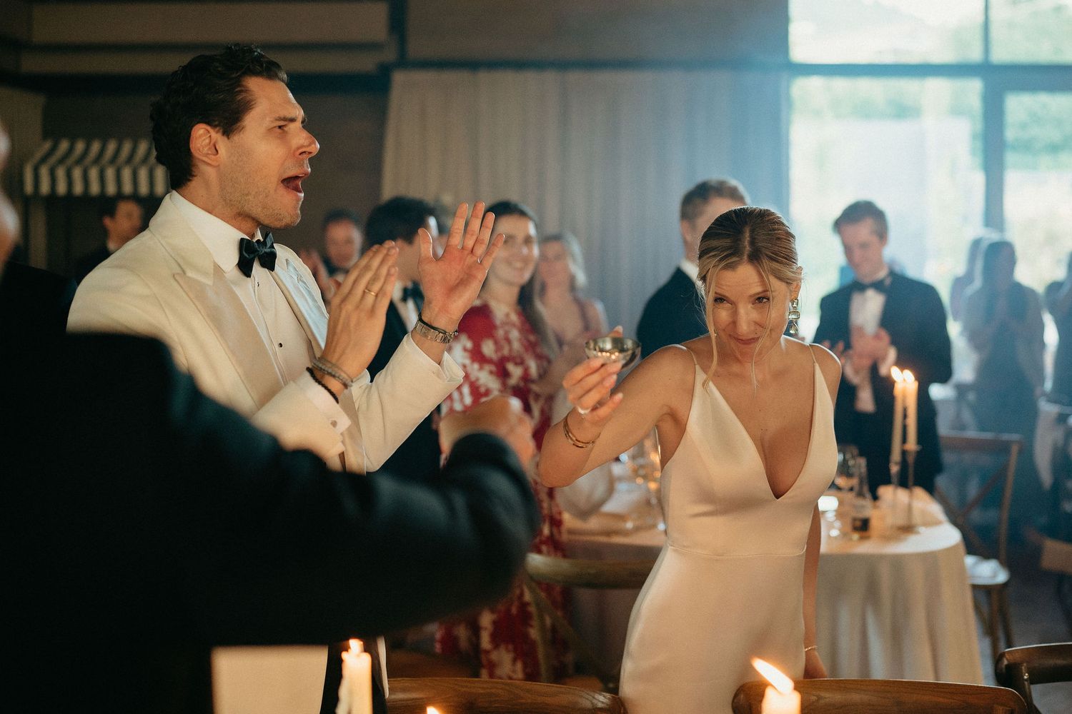 Wedding guests dancing and celebrating together on the dance floor at an indoor reception venue.