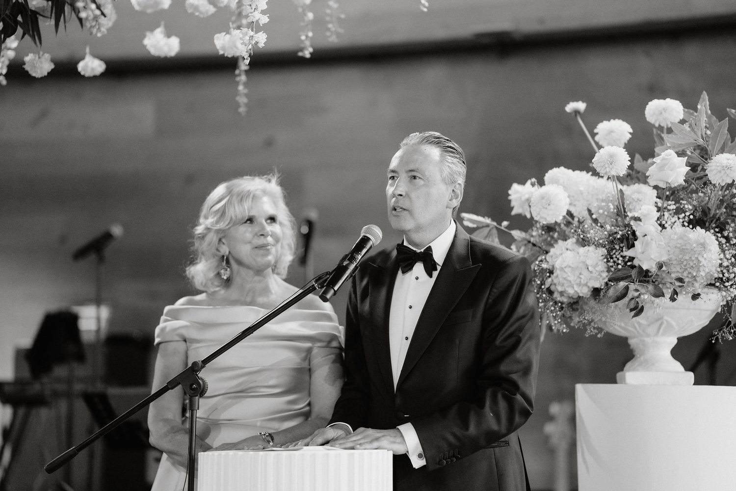 A couple dances together at a wedding reception under elegant crystal chandeliers and floral decorations.