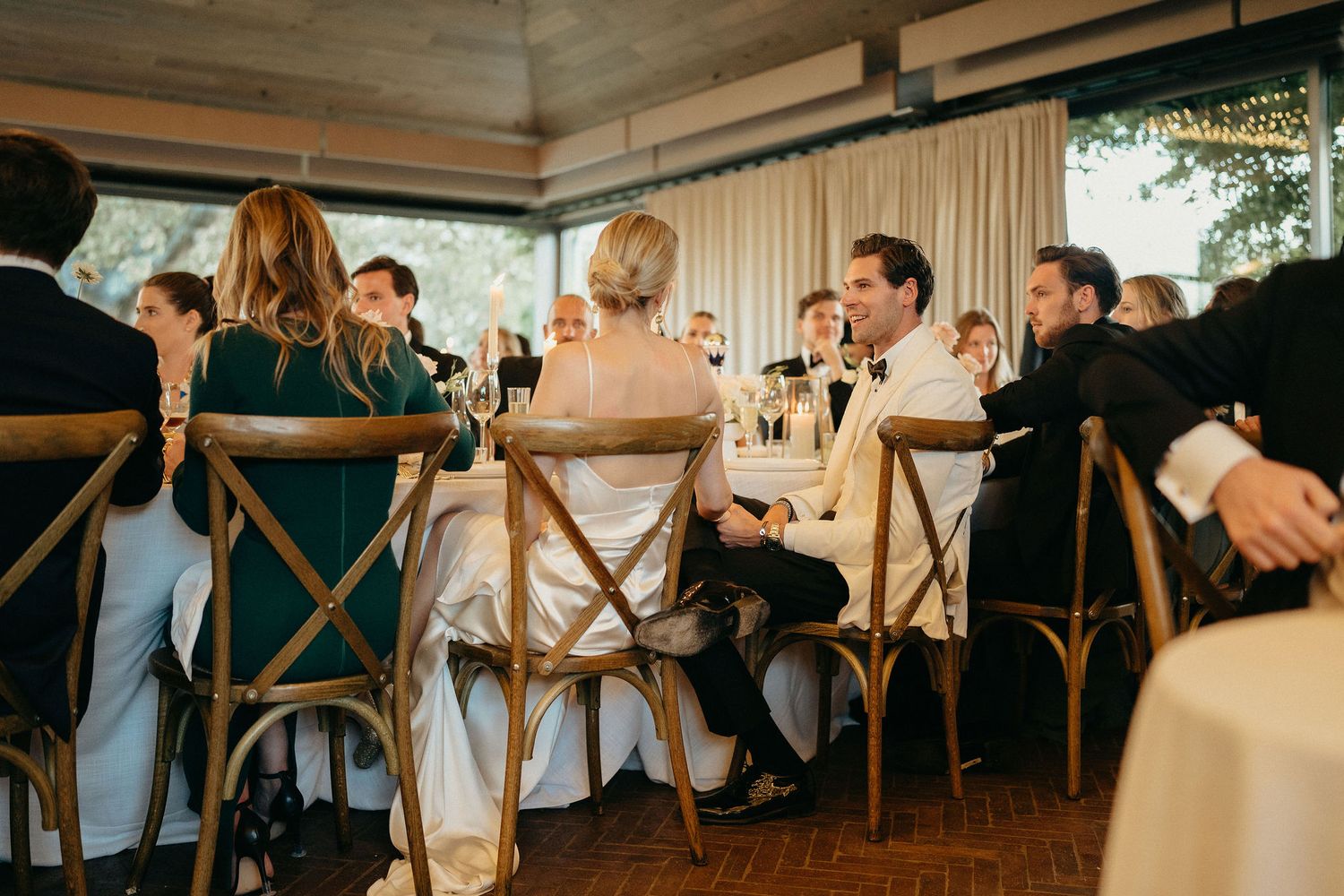 Wedding guests dance and celebrate together on a rustic wooden dance floor at an elegant reception venue.