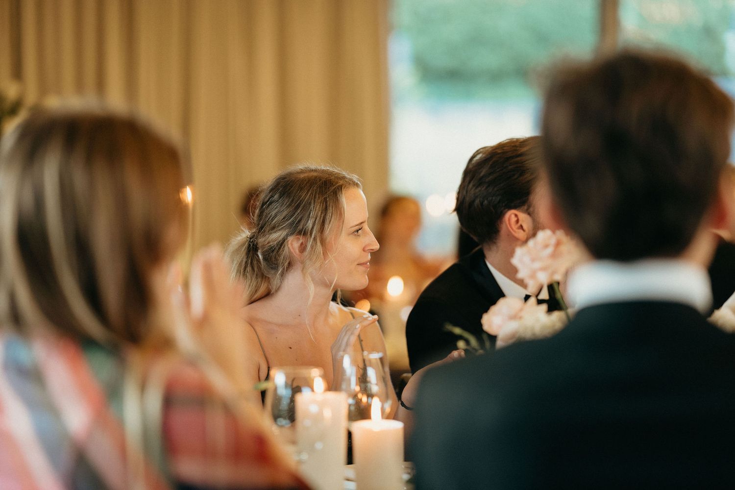 Soft focus wedding reception scene with candlelit tables and guests creating a warm, romantic atmosphere.