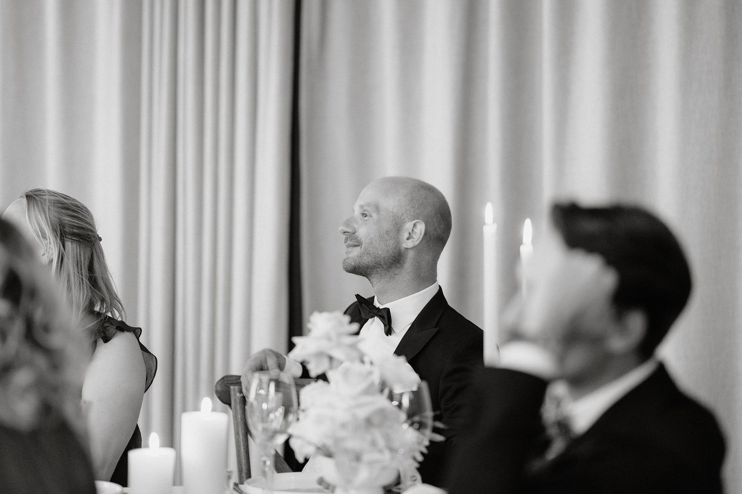 Black and white wedding photo collage showing candid moments of guests laughing and dancing at a celebration.