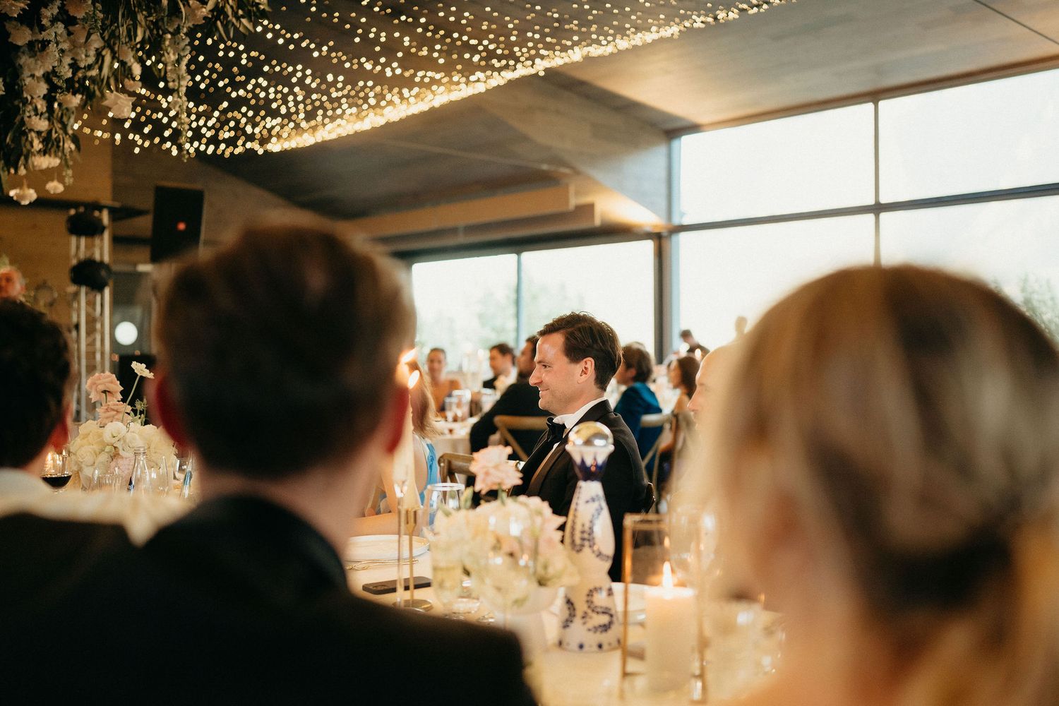 Wedding reception venue decorated with twinkling string lights as guests gather for dinner celebrations.