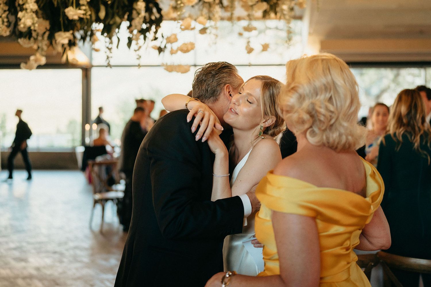 Guests dancing and celebrating at an elegant wedding reception with warm lighting and formal attire.
