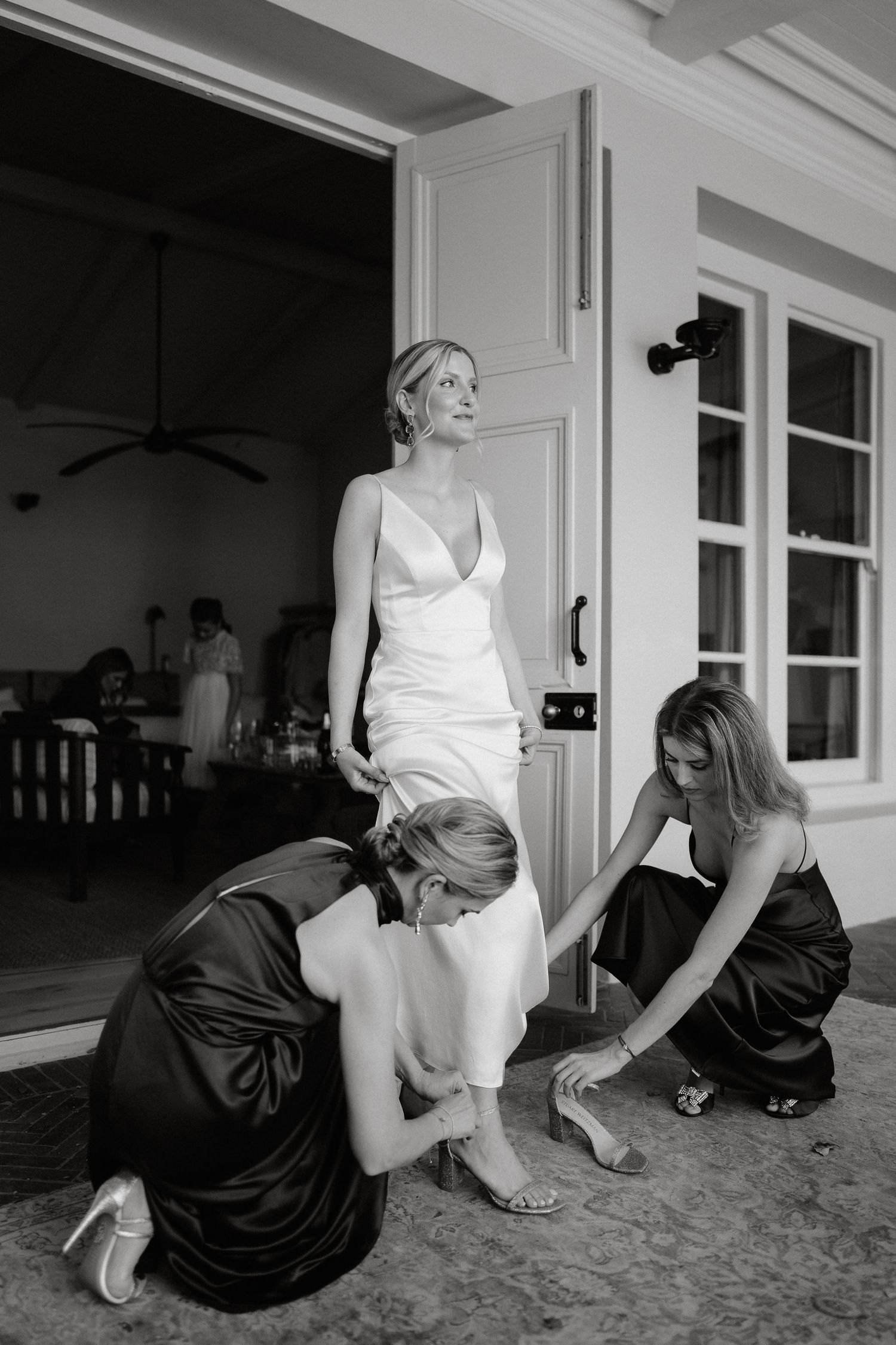 A black and white photo sequence shows a person in a white top and another in a dark dress interacting on the floor.