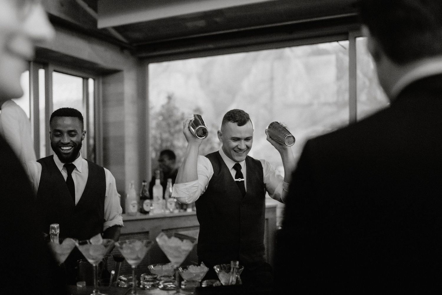 Black and white photo of wedding guests seated at long tables during an intimate indoor reception.