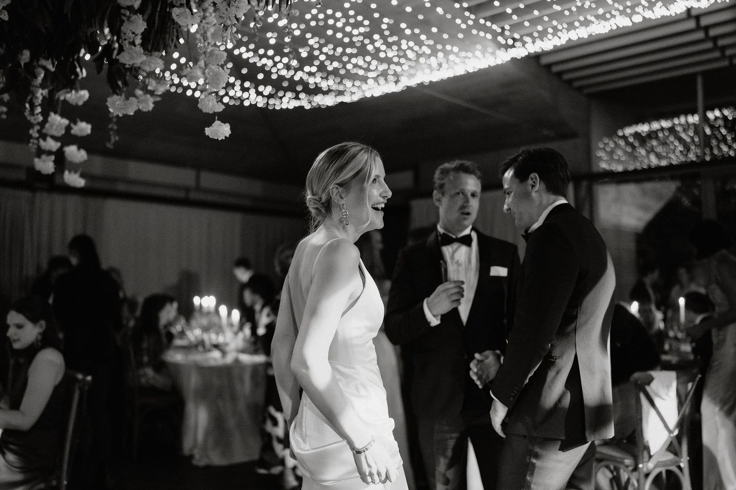 A couple shares their first dance at a wedding reception under twinkling lights and decorations.