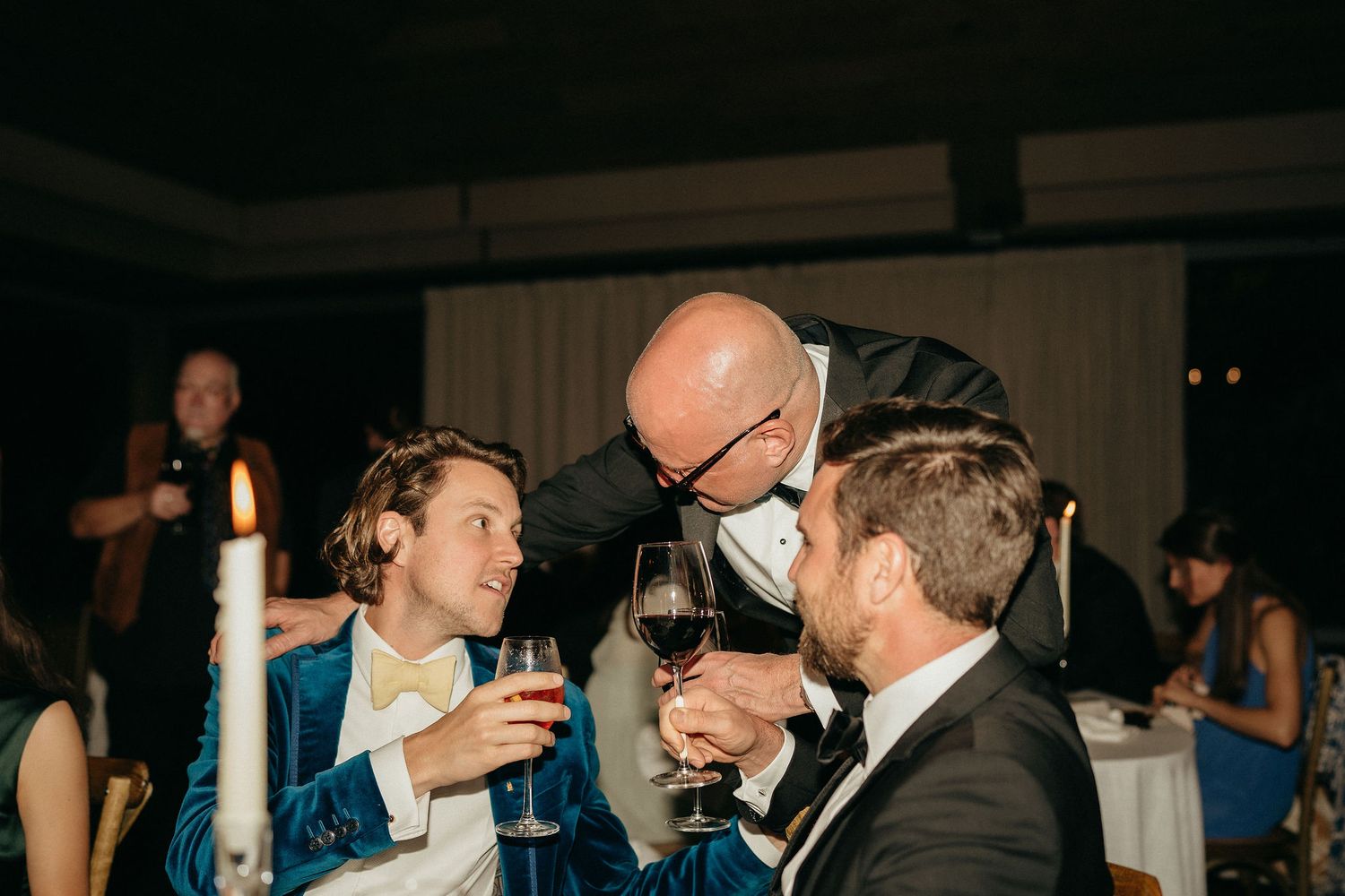 A group of people dancing and socializing at a dimly lit party or reception venue.