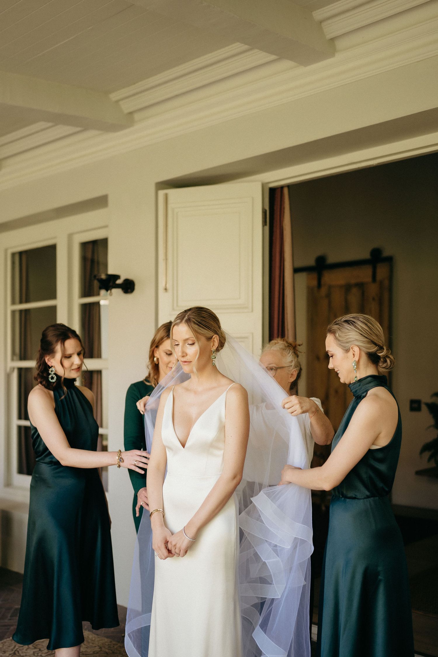 A sequence of wedding preparation photos showing a bride and bridesmaids in navy dresses getting ready in a bright room.