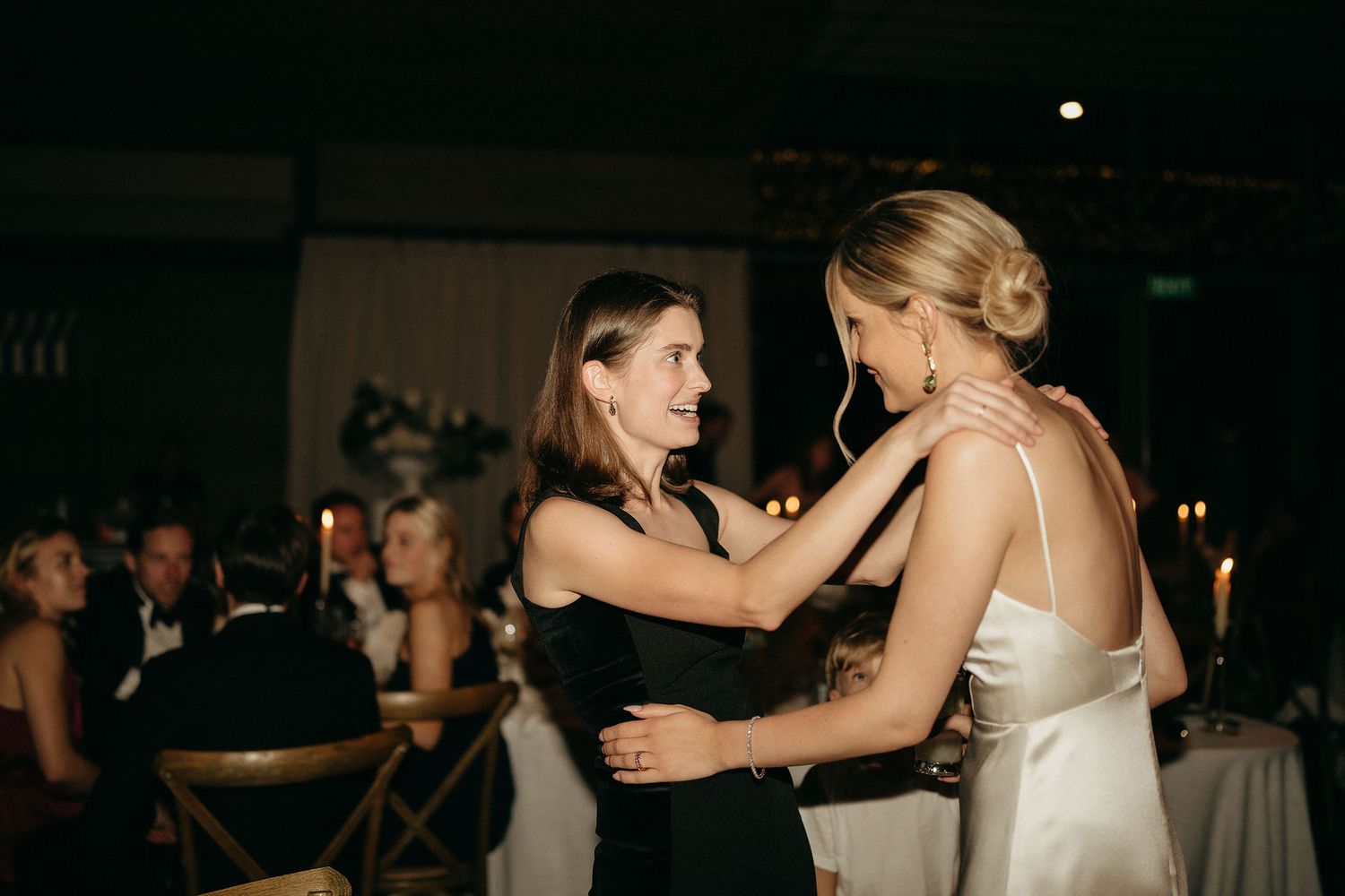 Couples dance together during an elegant wedding reception in a dimly lit ballroom.