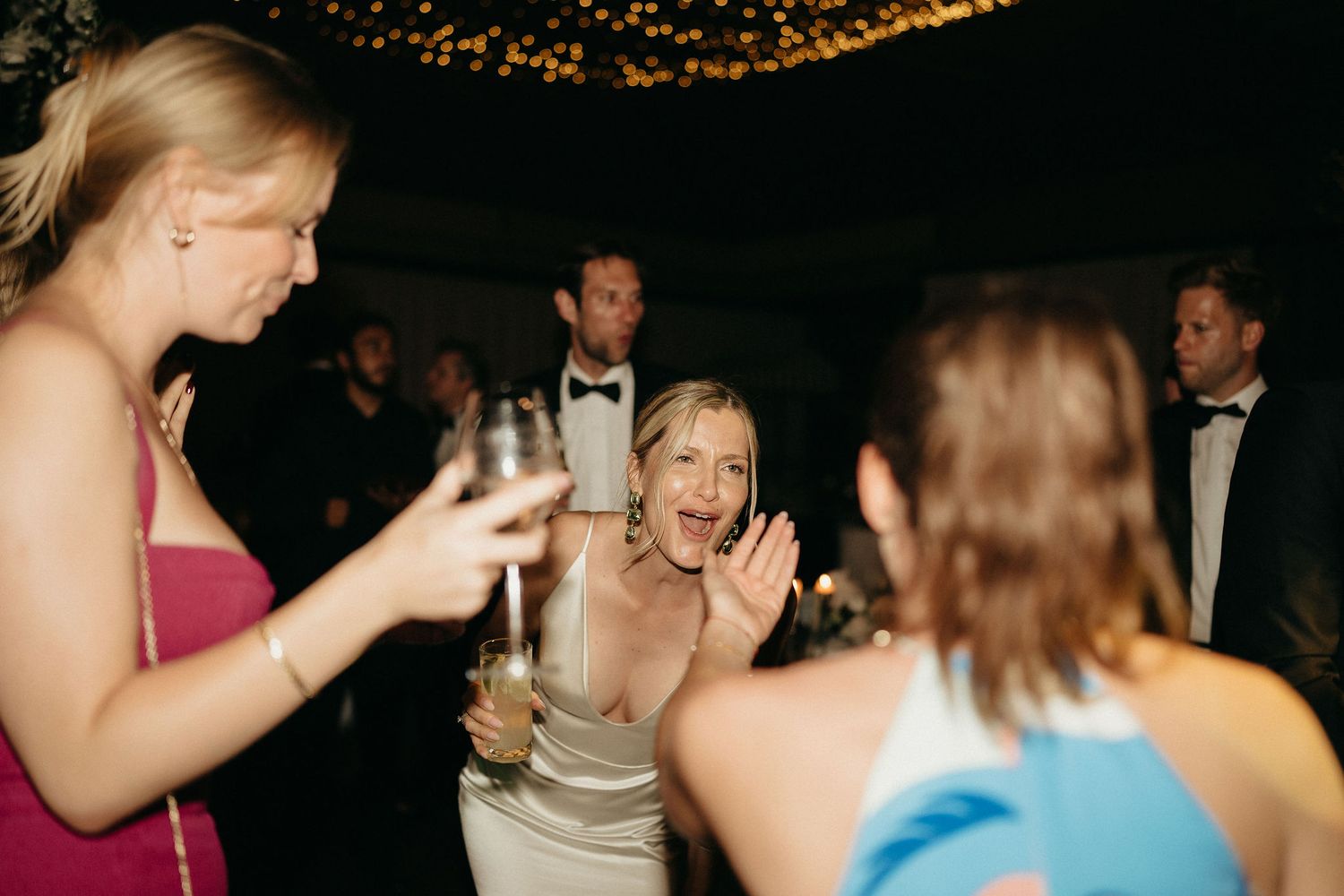 People dancing and socializing at a dimly lit party or celebration event.