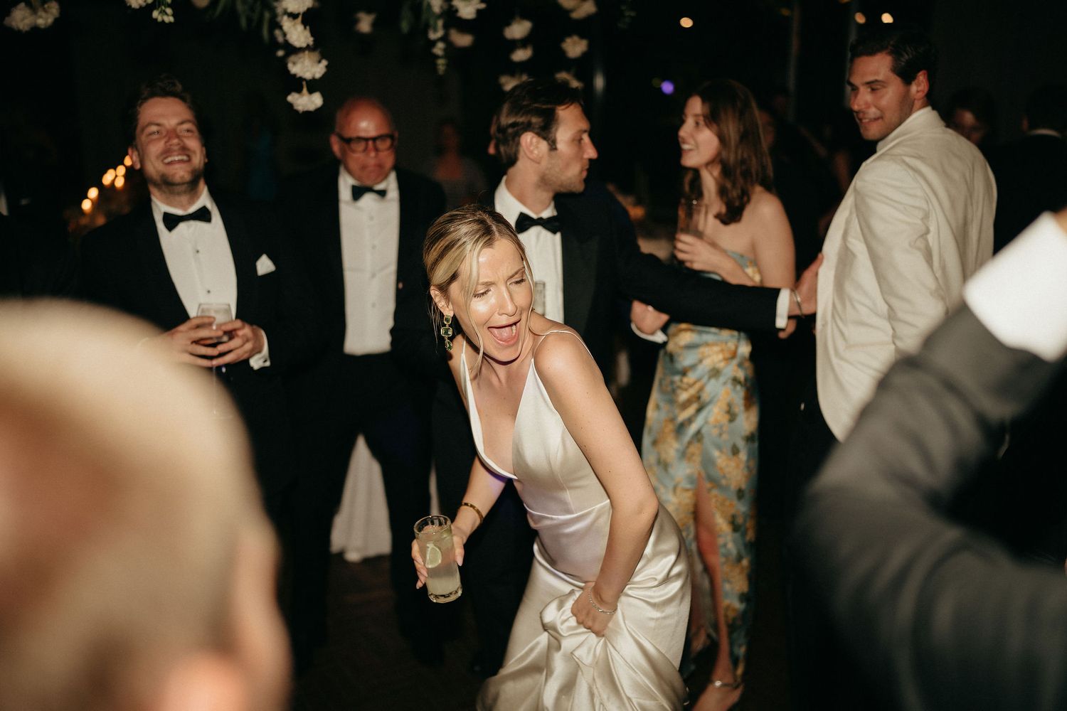 Wedding guests mingle and dance at an elegant evening reception in formal attire.