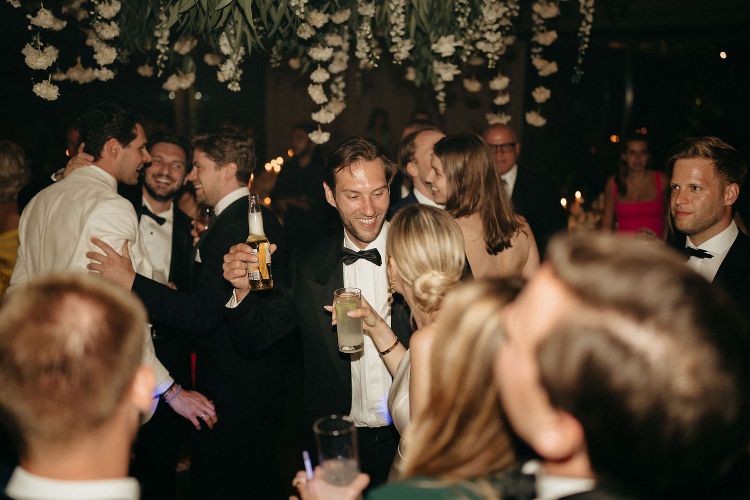 A crowded wedding reception dance floor filled with guests dancing and celebrating in formal attire.