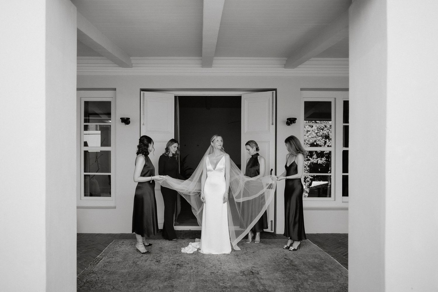 A sequence of black and white wedding photos showing bridal party preparations in an elegant indoor setting.