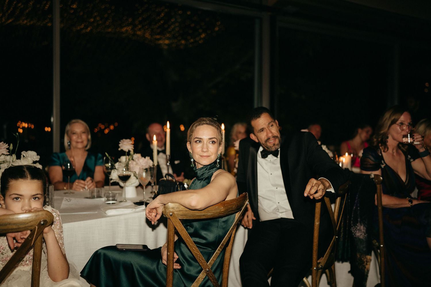 Guests dancing and celebrating at an elegant evening wedding reception with dark ambient lighting.