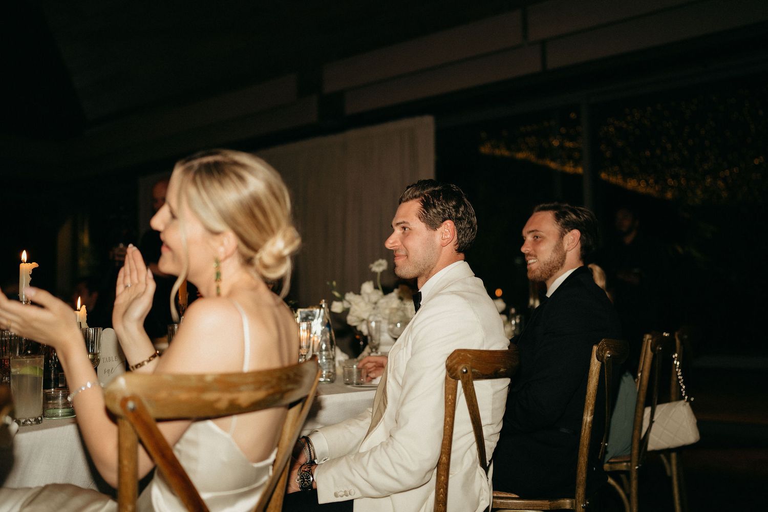 Wedding guests dance and celebrate on a dimly lit dance floor during an evening reception.