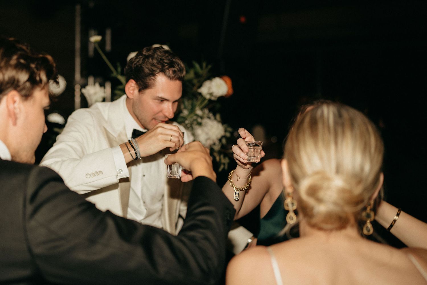 A couple dances together at an elegant wedding reception, surrounded by other guests in formal attire.