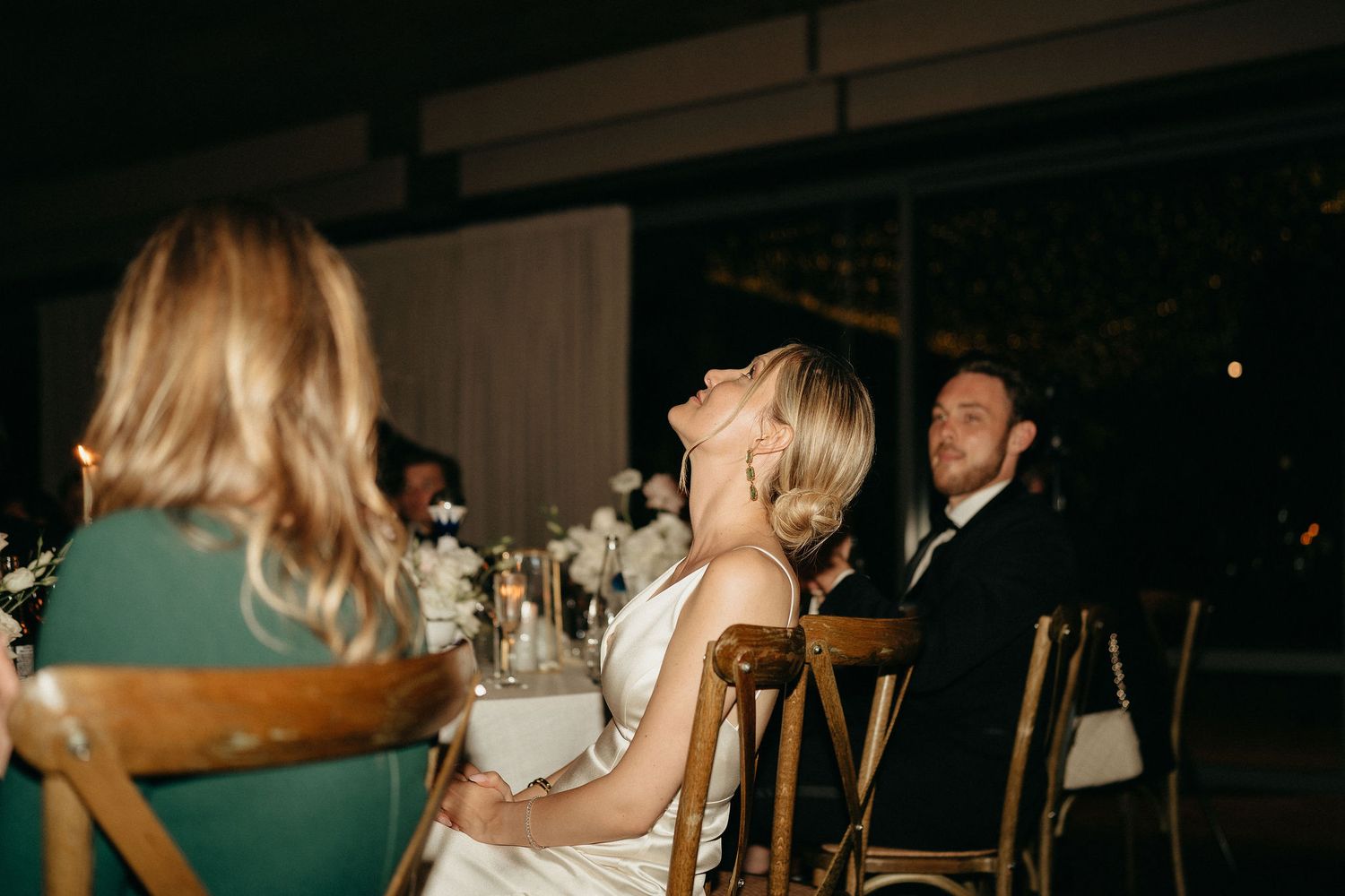 Wedding reception venue with dimly lit tables and elegant table settings.