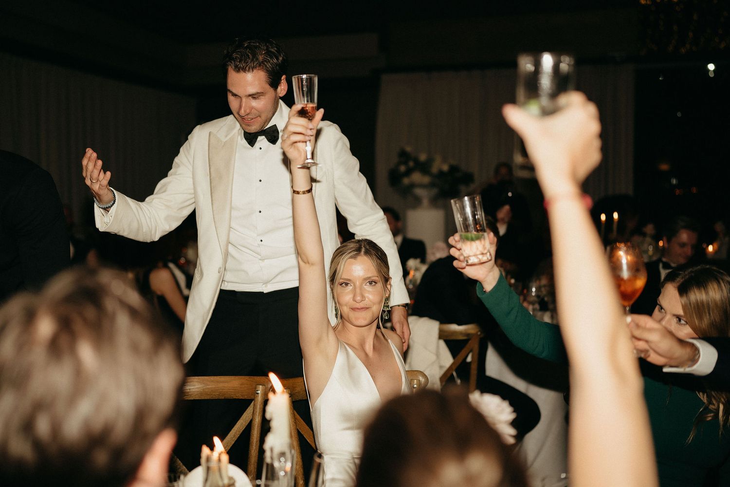 A lively wedding reception scene with people dancing and celebrating on a dark dance floor.