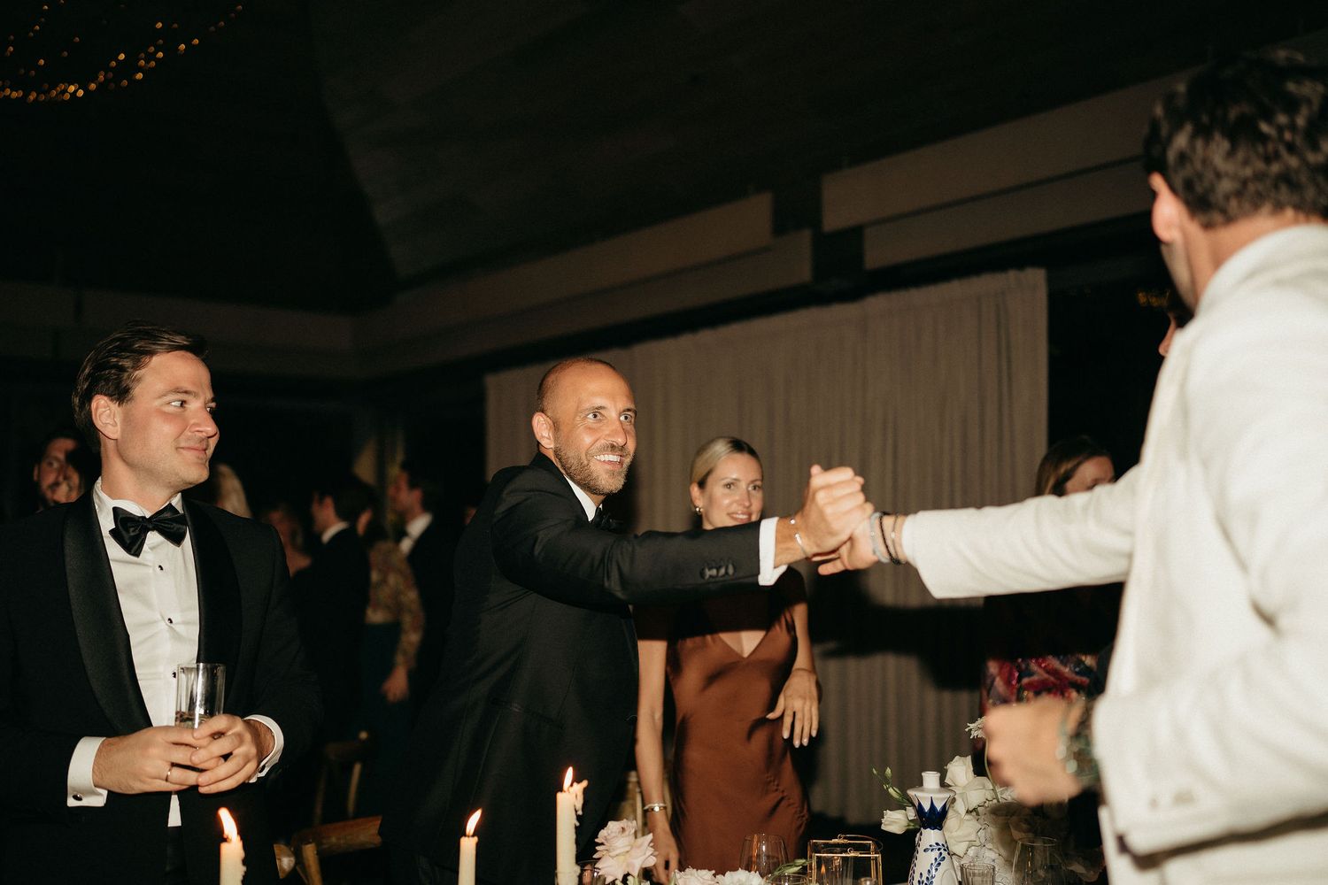 People dancing and socializing at an elegant formal event in a dimly lit venue.