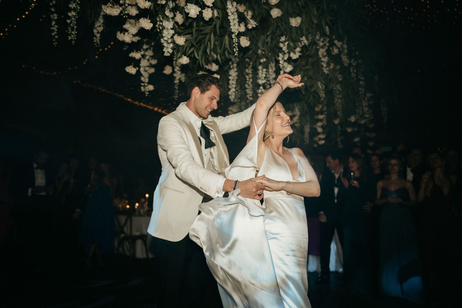 A couple dances together during a romantic wedding reception in formal attire.