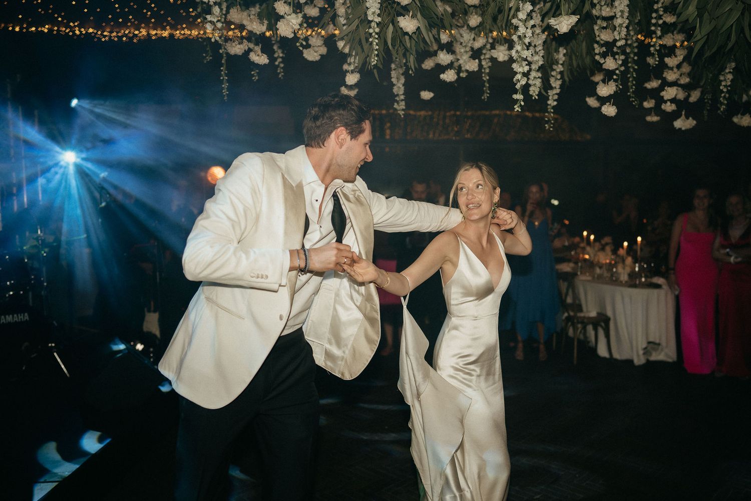 A couple shares a romantic dance moment on a dimly lit dance floor at a wedding reception.