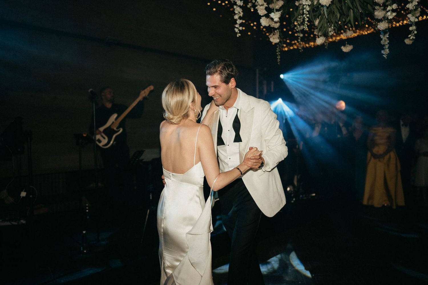 A couple shares a romantic dance moment on a dimly lit dance floor with blue lighting effects.