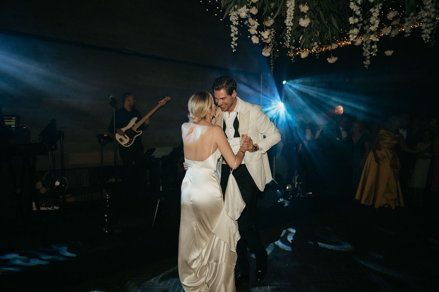 A couple shares their first dance at a wedding reception while guests watch from the surrounding tables.