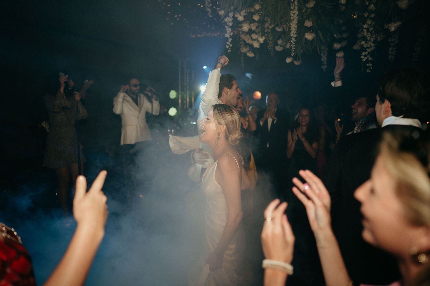 Concert crowd holds up phones with flashlights illuminated during a dark performance at a music venue.