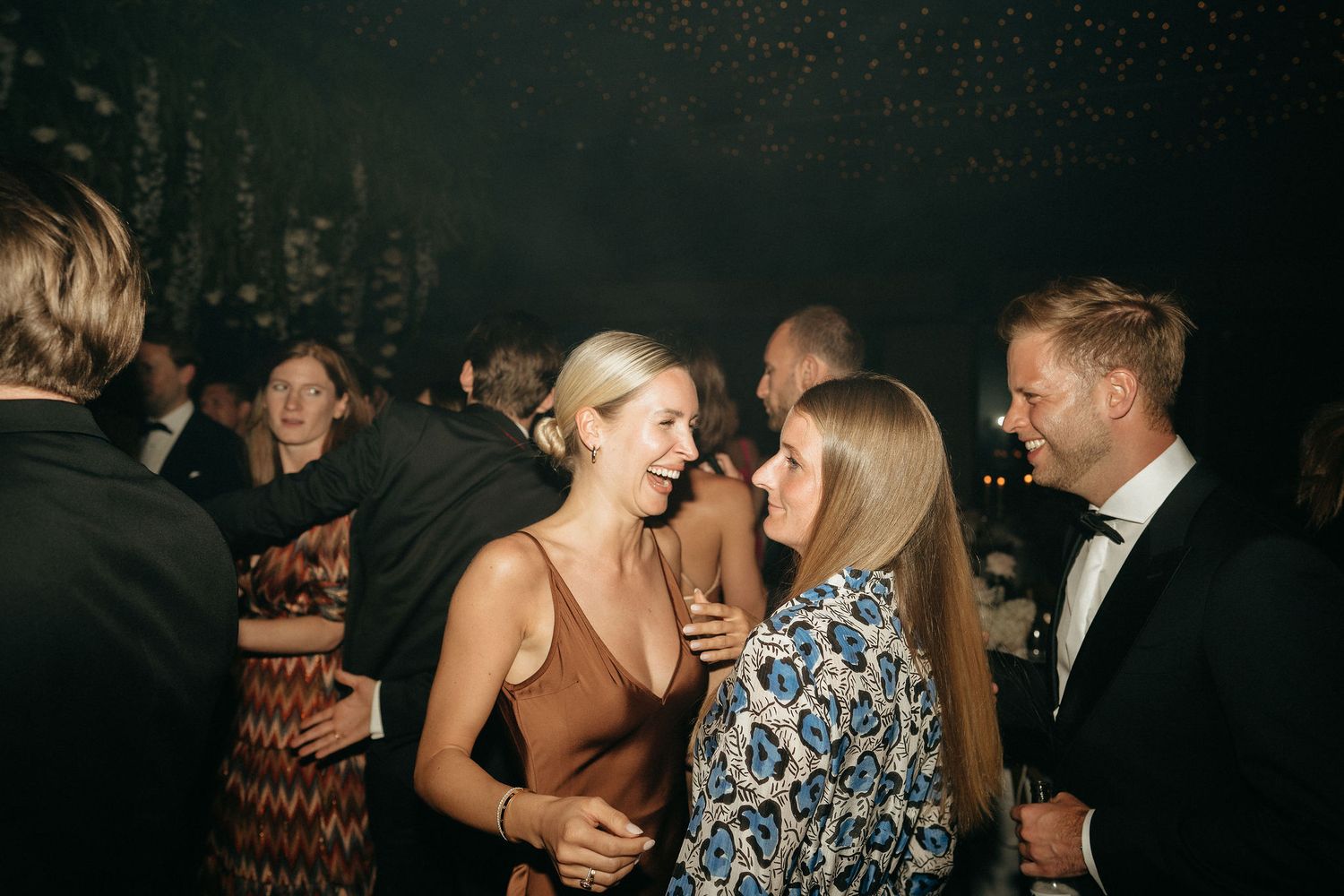 Guests dancing and socializing at an elegant evening party in a dimly lit venue.