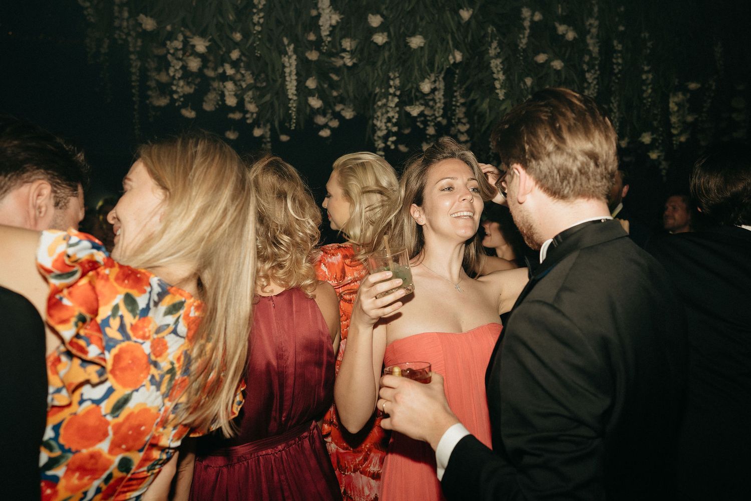 A group of people dancing and socializing at a dimly lit party or celebration event.