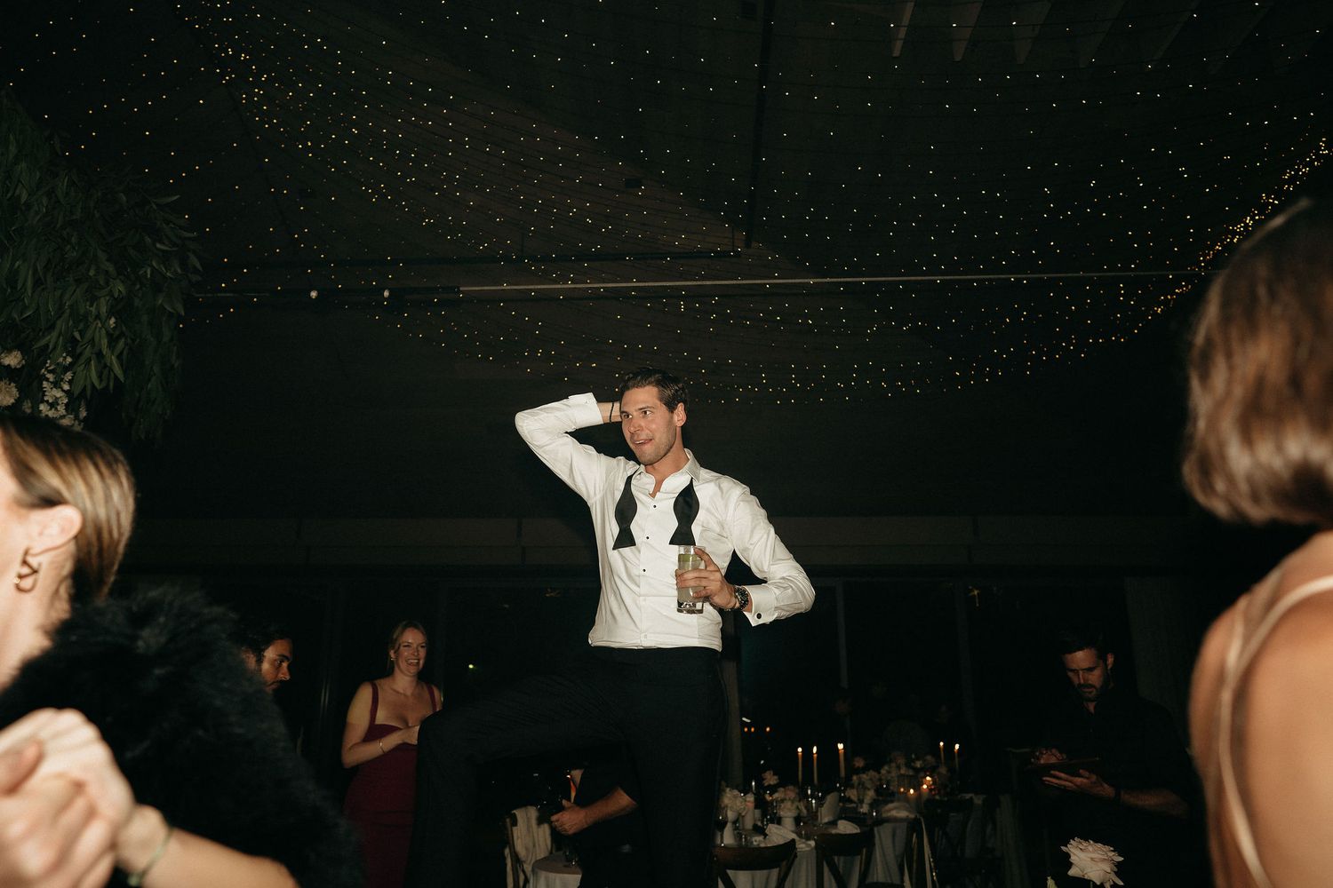 A dark nightclub scene with people dancing and socializing under dim lighting.