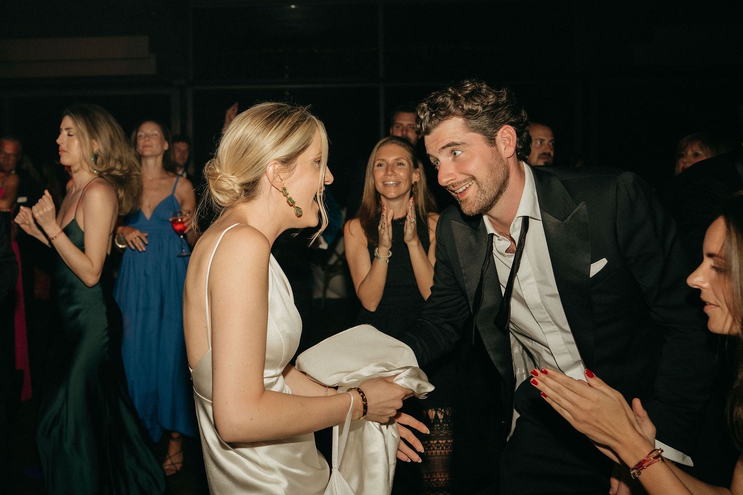 A group of people dancing and socializing at a dimly lit party or celebration event.