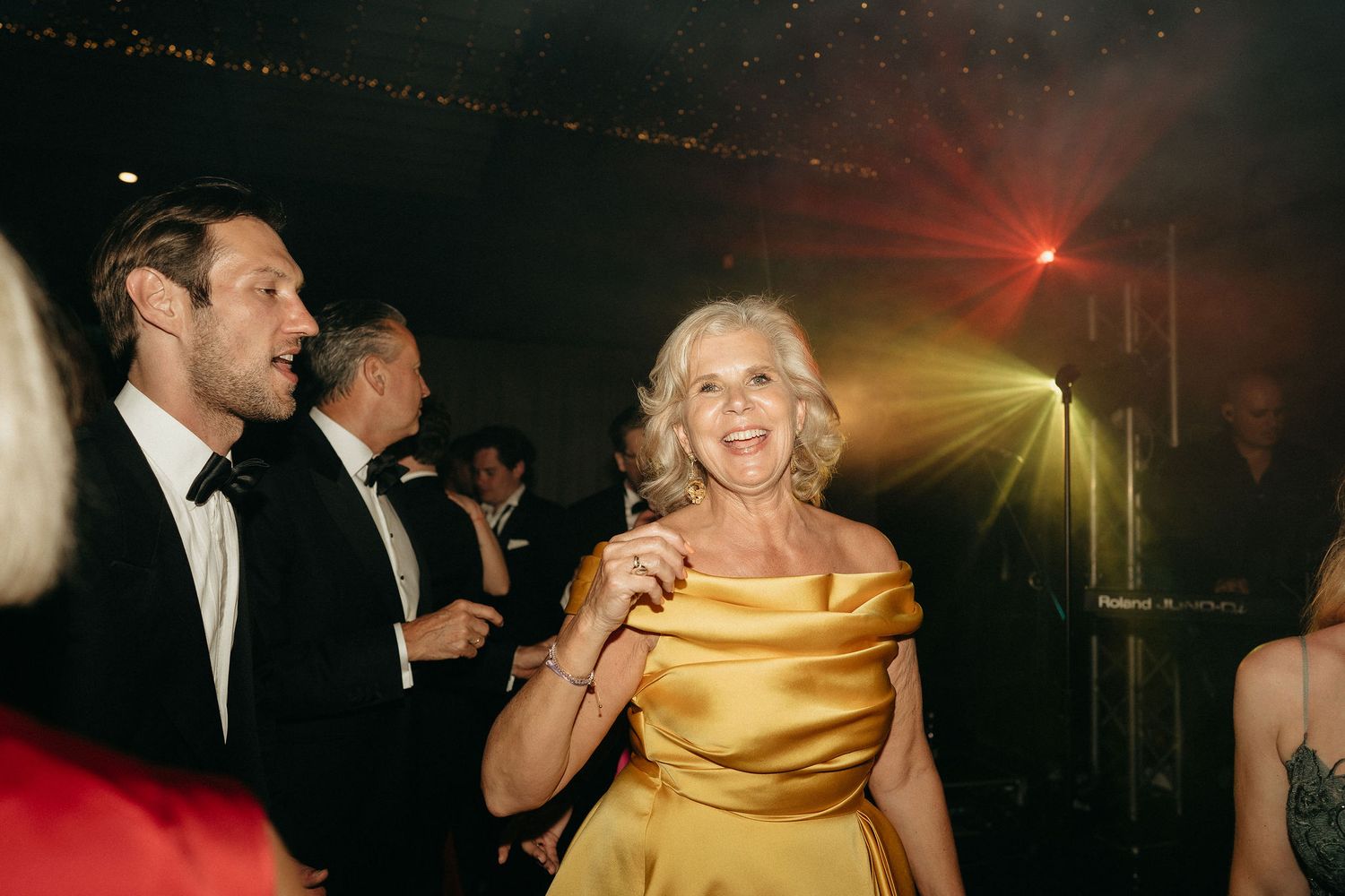 People dancing and celebrating at an elegant evening party with warm lighting and formal attire.
