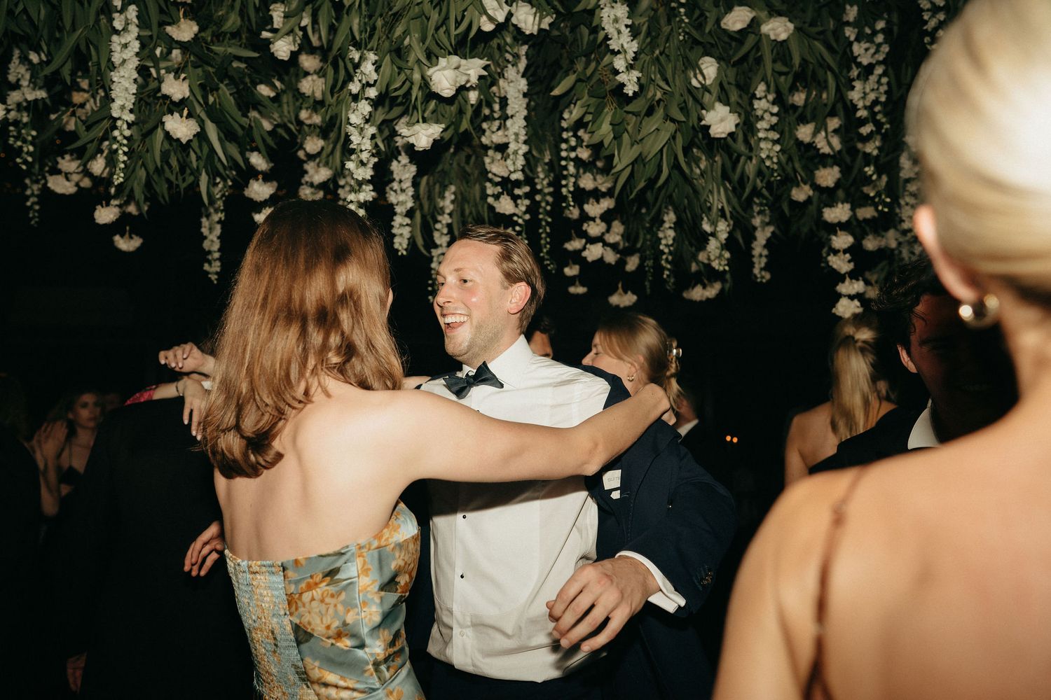 Couples dancing together under hanging floral decorations at an elegant evening event.