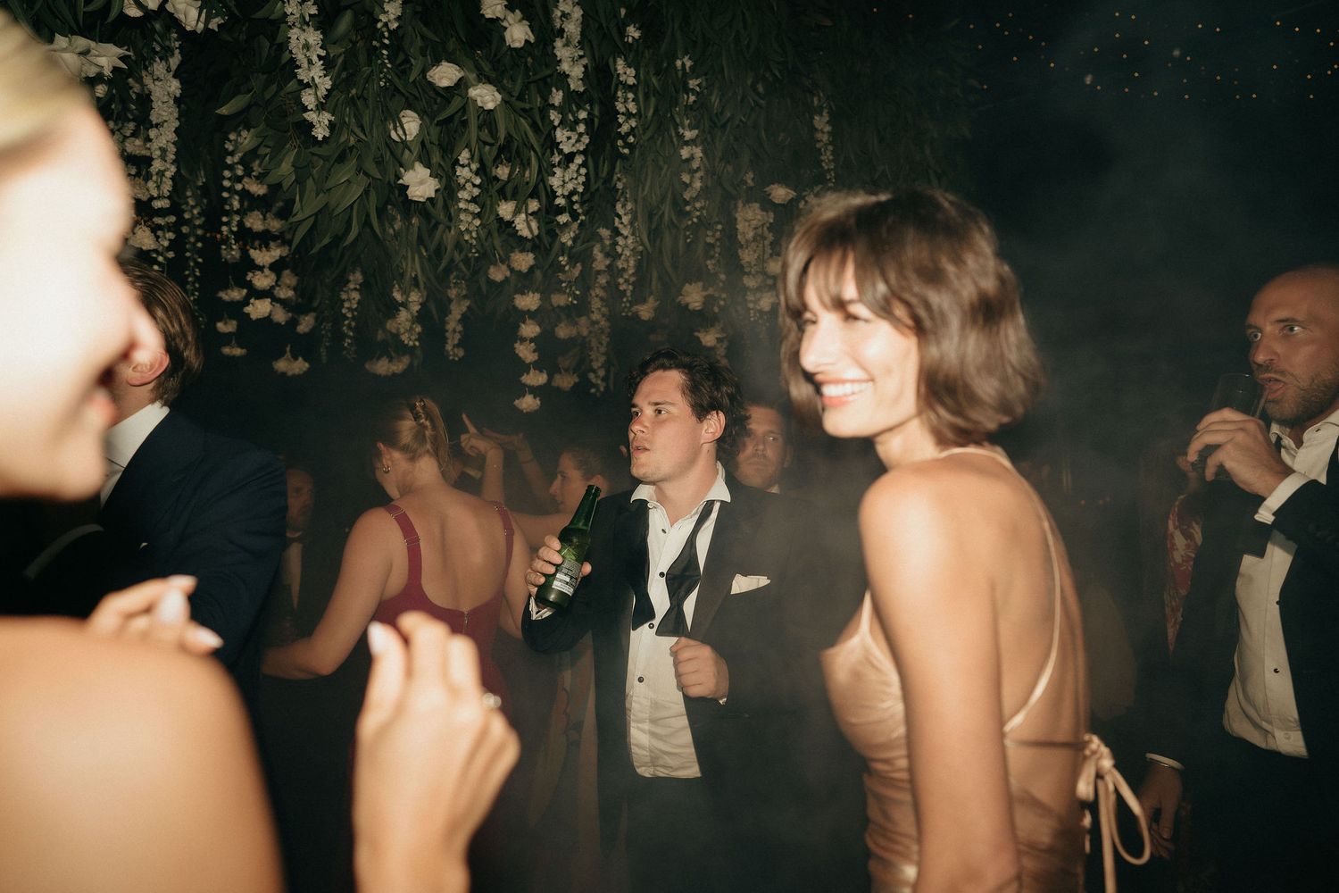 Vintage style party scene with people dancing and socializing in a dimly lit nightclub atmosphere.