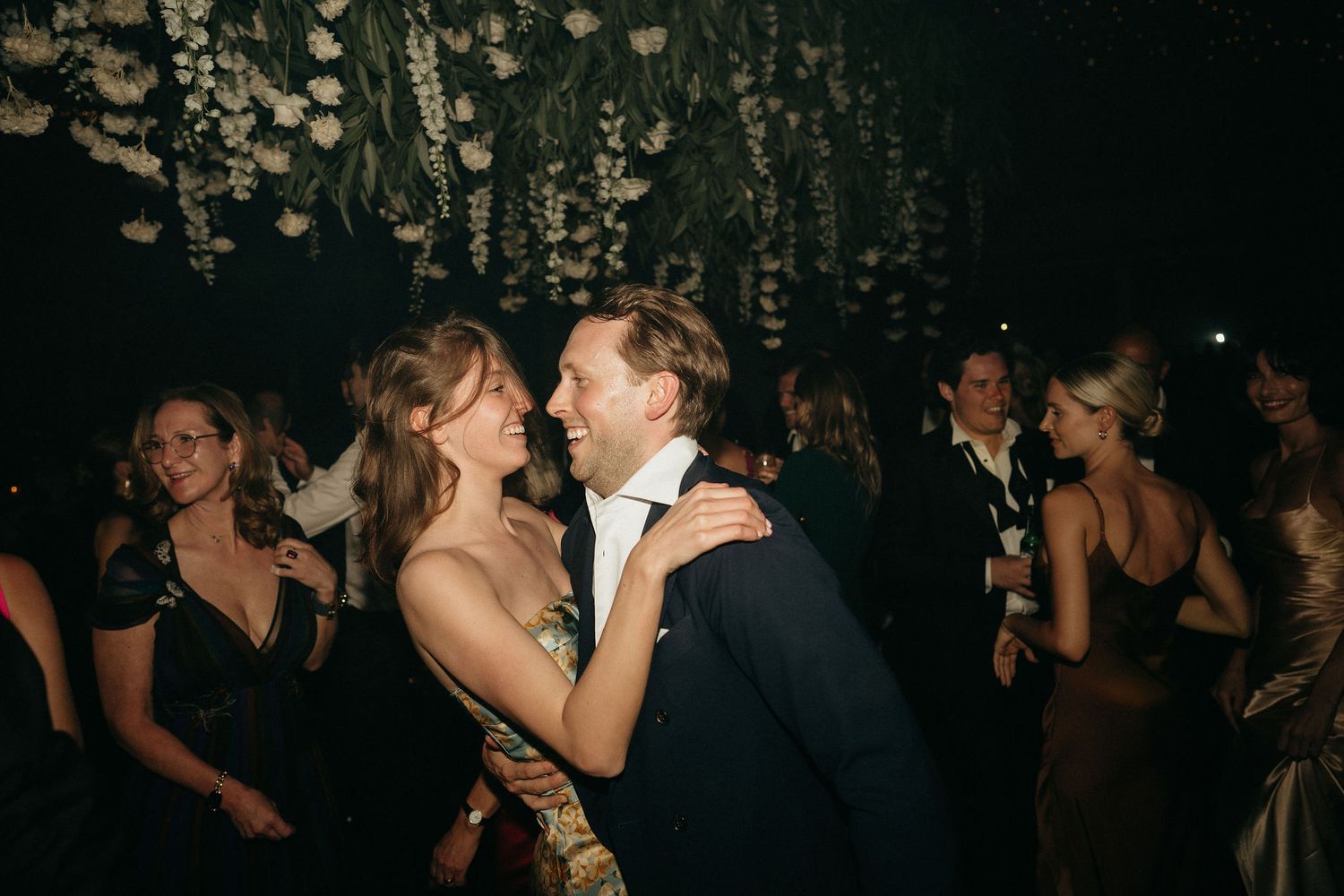 Couple sharing an intimate dance moment under hanging lights at an elegant evening reception.