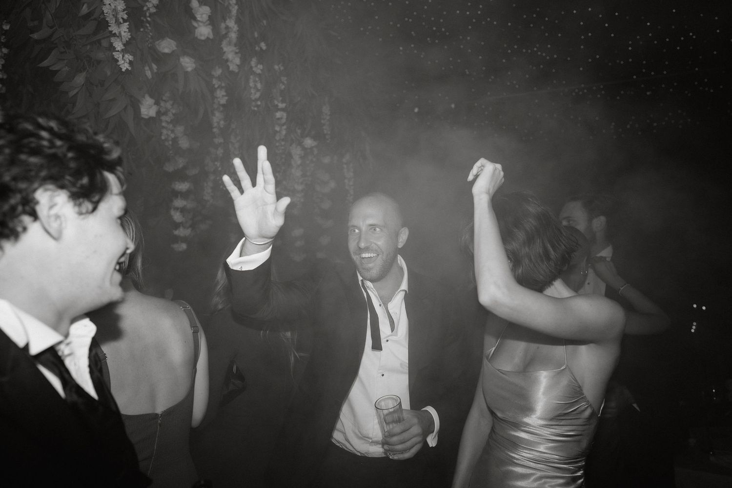 Black and white photo of energetic party guests dancing and celebrating at a formal event.
