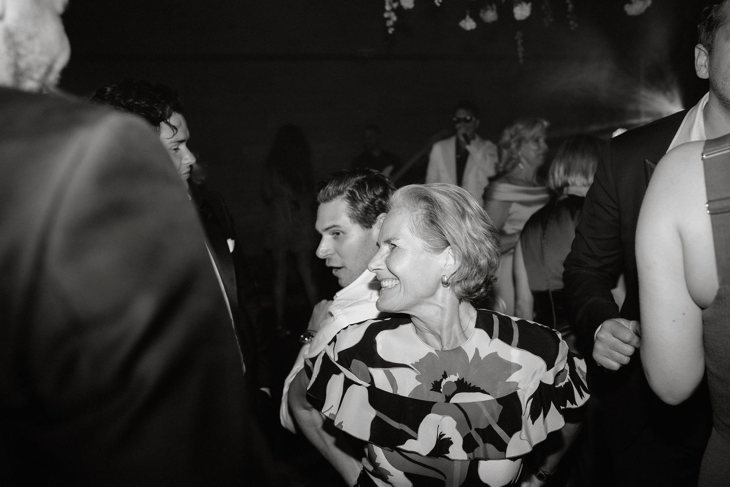 Lively dance floor scene at a wedding reception with guests dancing in black and white photography.