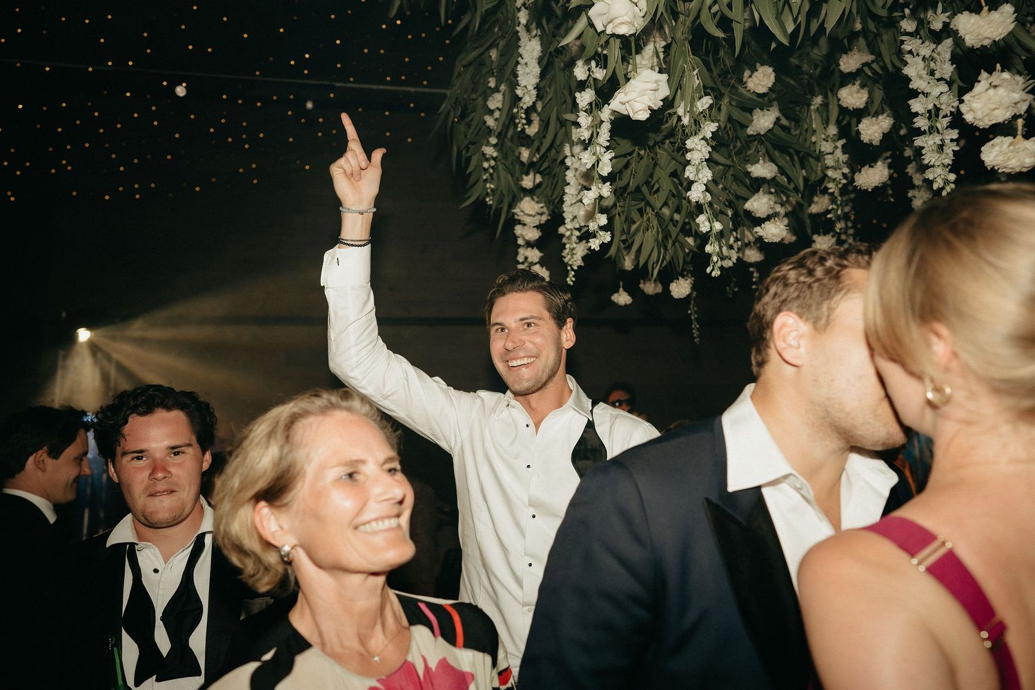 Wedding guests dance and celebrate on a crowded dance floor at an evening reception party.