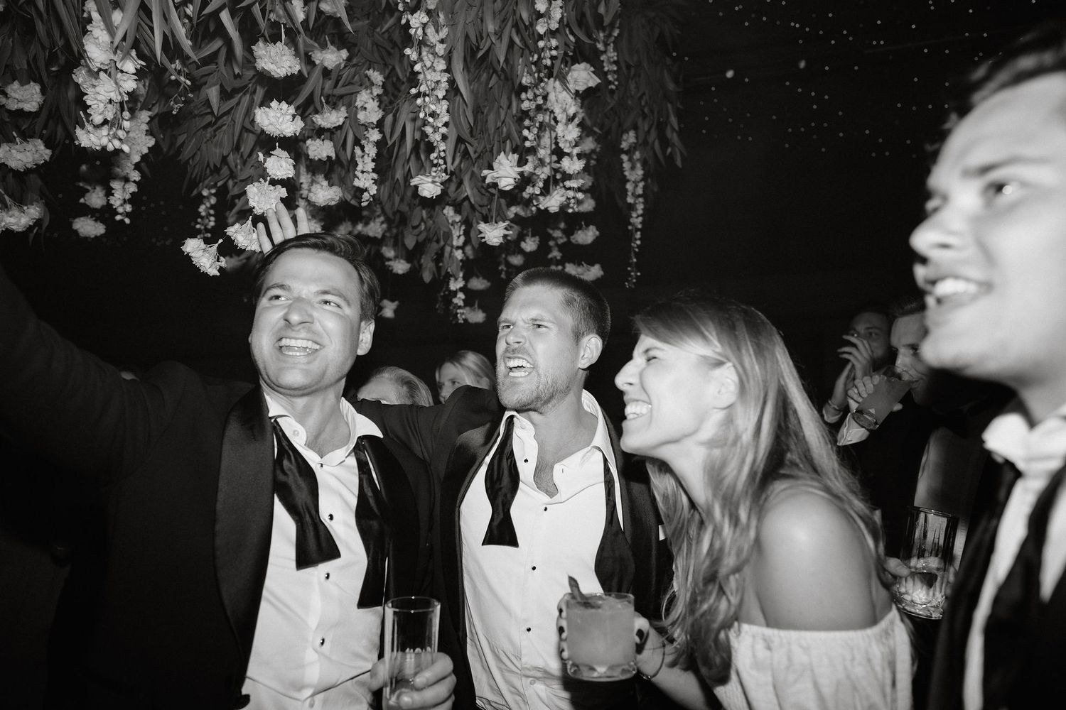 Black and white photo of party guests looking up and laughing during a celebration.