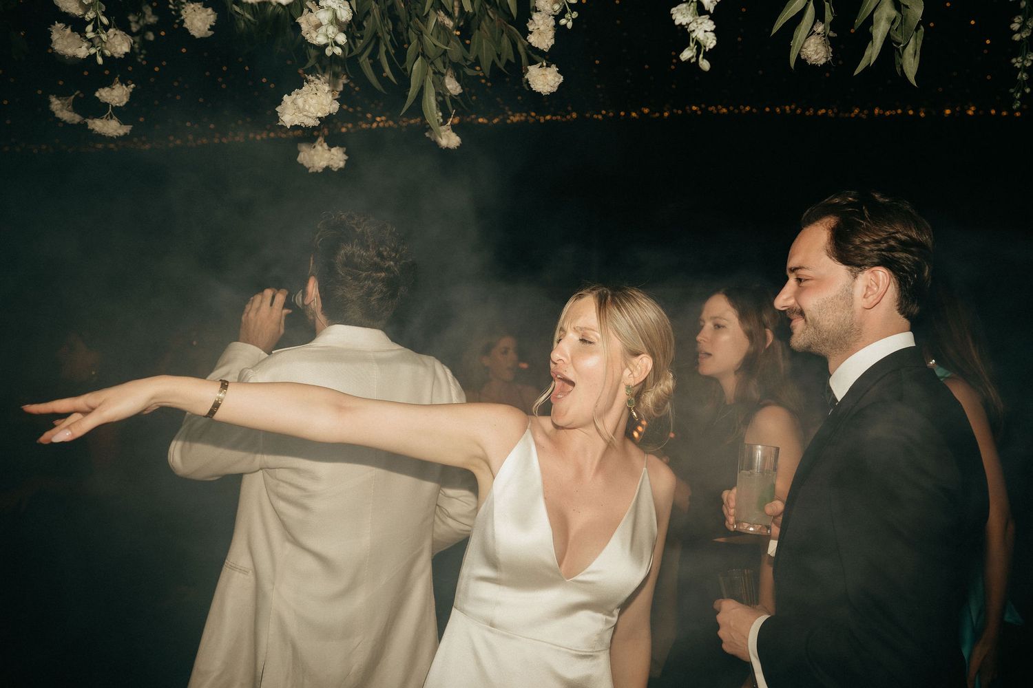 Wedding guests dancing and celebrating on a dark dance floor during an evening reception party.