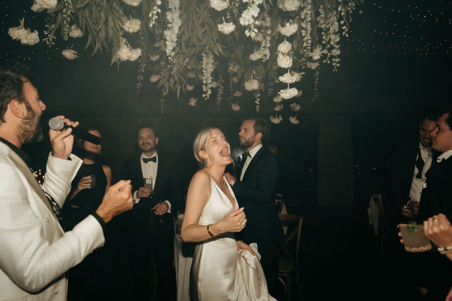 Couple shares a romantic dance under twinkling lights at an elegant evening wedding reception.