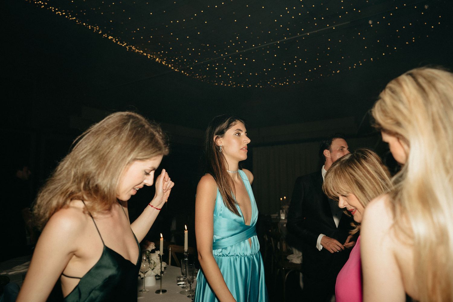 A group of people dancing together in a dimly lit nightclub or party venue with colorful lighting.