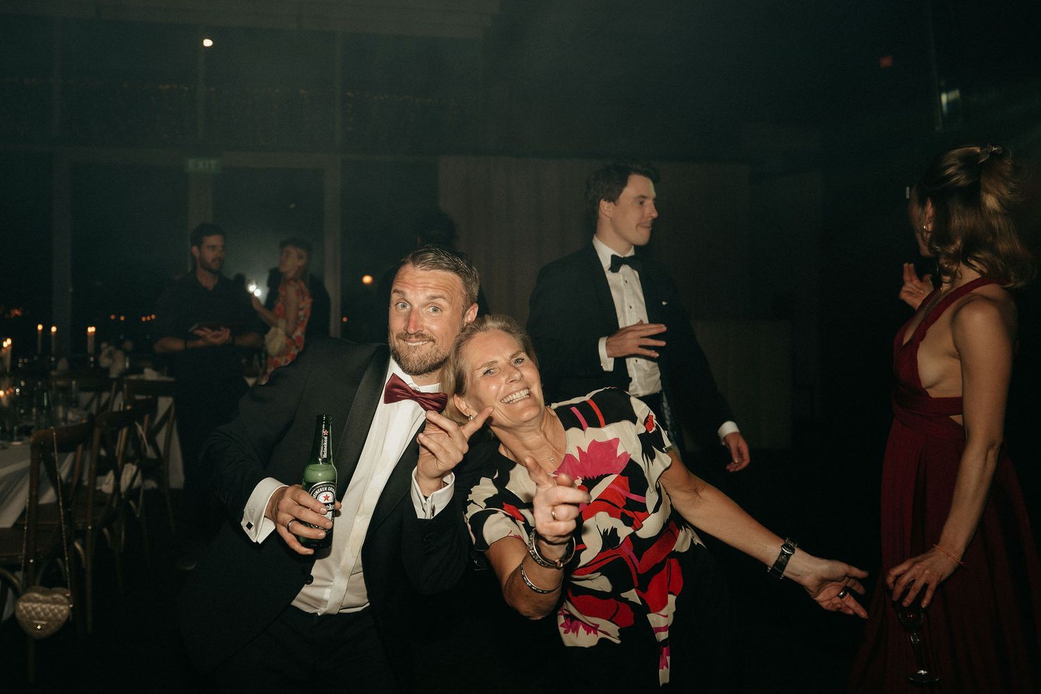 People holding drinks and socializing in a dark nightclub atmosphere.