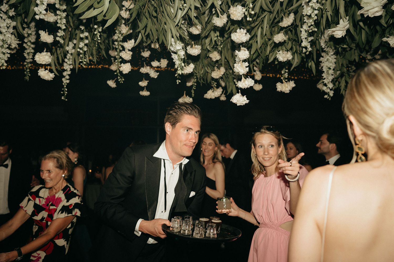 People dancing and socializing at a dimly lit party venue with decorative hanging elements from the ceiling.