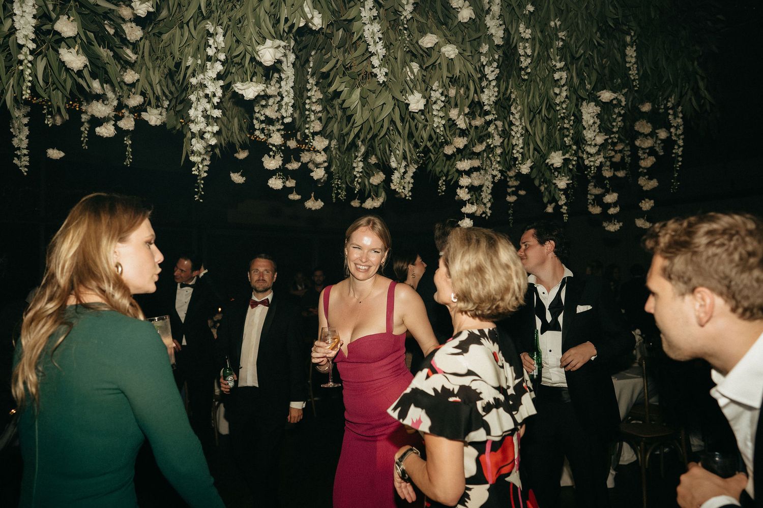 Guests mingling and dancing under ornate ceiling decorations at an evening celebration.