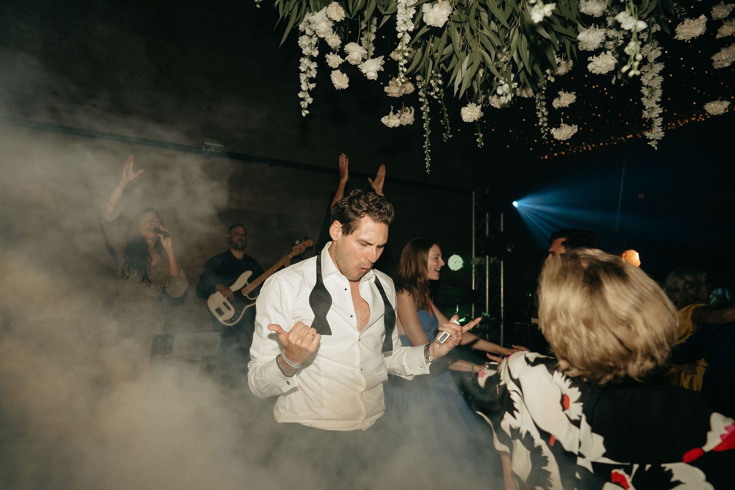 A person dances energetically in a dimly lit nightclub atmosphere with flashing lights and smoke effects.